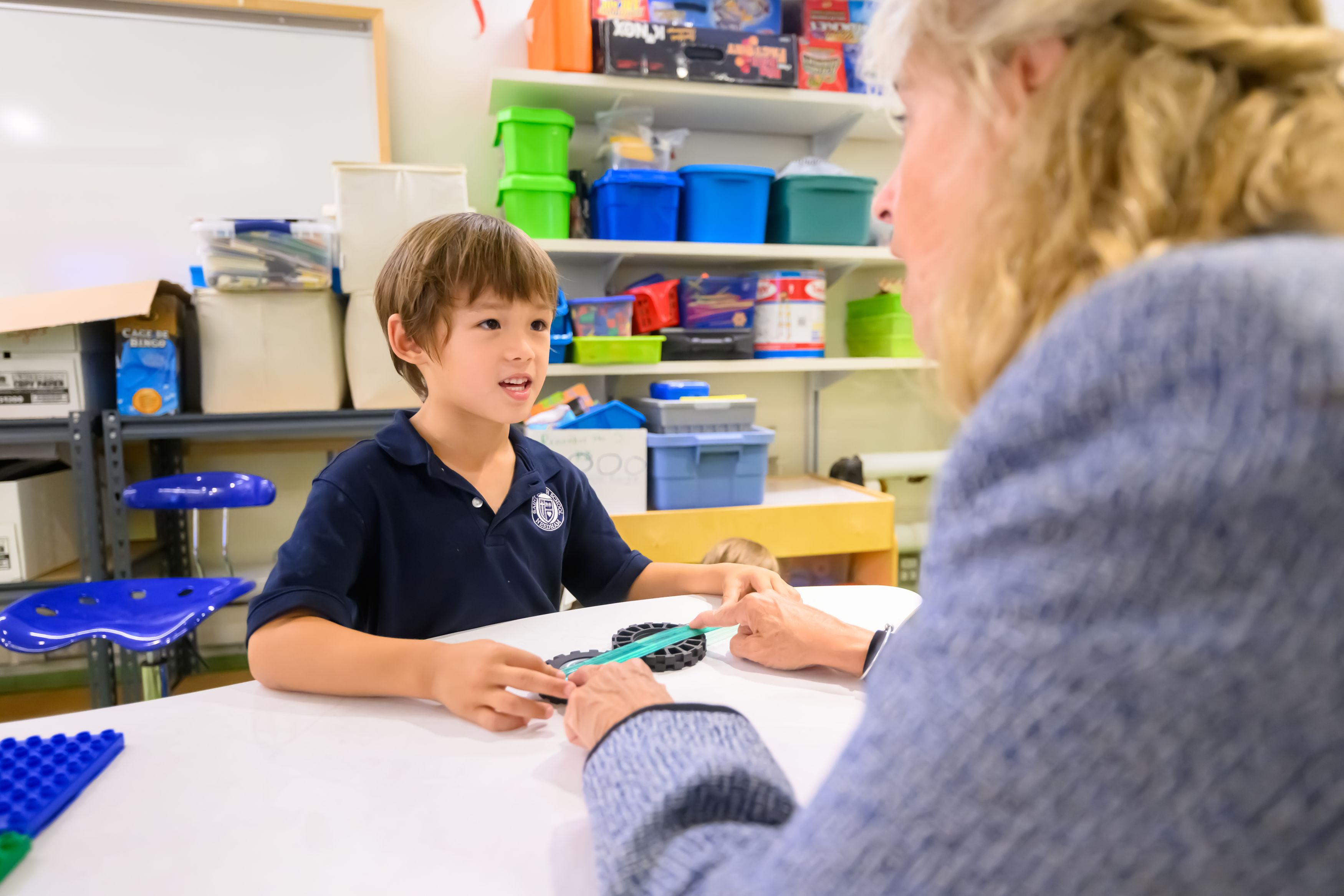 A boy in the STREAM lab working with a teacher measuring toy wheels